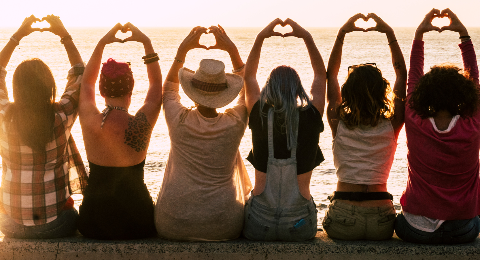 Group of Women Doing Heart Shape in Hands over Sunset
